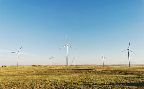 Wind turbines on field against sky