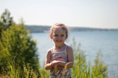 Portrait of smiling girl standing against sky