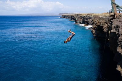 Man jumping in sea against sky