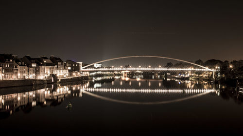 Illuminated bridge over lake against sky at night