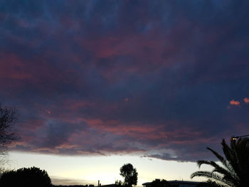 Low angle view of silhouette trees against dramatic sky