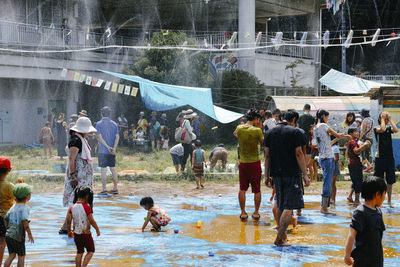 Water spraying from pipes over people on muddy field