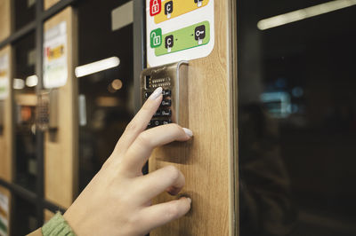 Hand of woman entering password on keypad of locker at supermarket