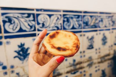 Cropped hand of woman holding snack against wall