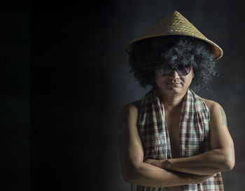 Portrait of young man wearing sunglasses standing against black background