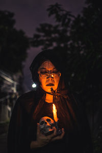 Portrait of woman wearing glasses standing at night
