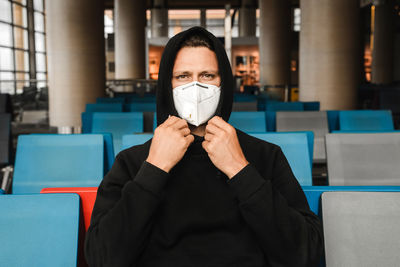 Men in respirator mask n95 sitting at the empty airport terminal. coronavirus covid-19 concept.