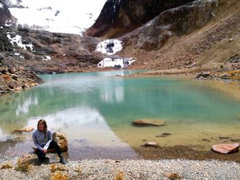 People sitting on lake by mountain