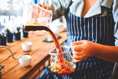 Midsection of woman preparing coffee on table