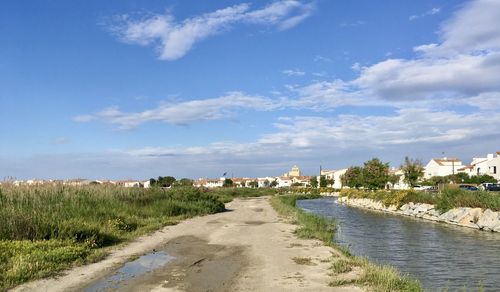 Scenic view of river with town in the background against blue sky