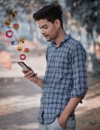 Young man looking away while standing on mobile phone