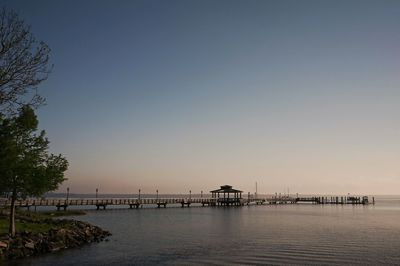 Pier over sea against clear sky during sunset