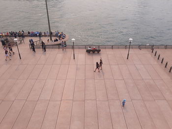 High angle view of people walking on footpath by sea