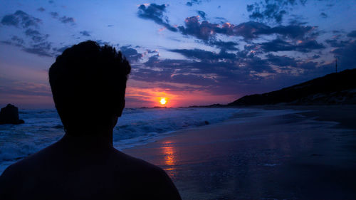 Silhouette man by sea against sky during sunset