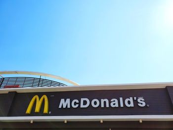 Low angle view of text on building against clear blue sky
