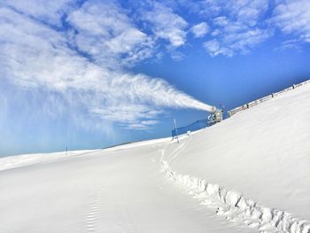 Snow covered landscape against blue sky