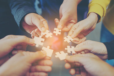 Cropped image of friends playing jigsaw puzzle