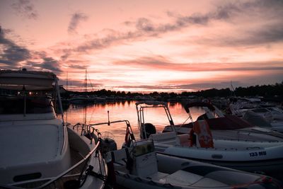 Boats moored at harbor against sky during sunset