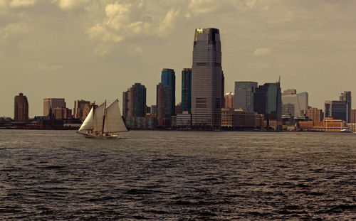 Modern cityscape by sea against sky