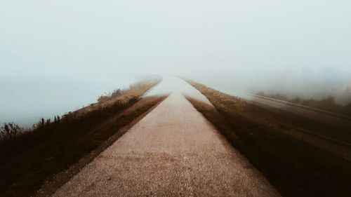 Dirt road along landscape against sky