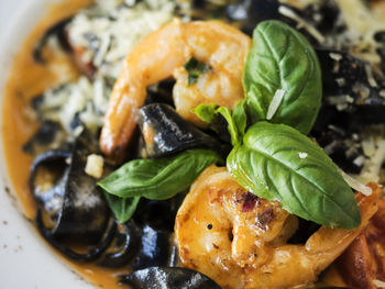 High angle close-up of black fettuccine with seafood in bowl