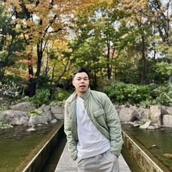 Portrait of young man standing against trees