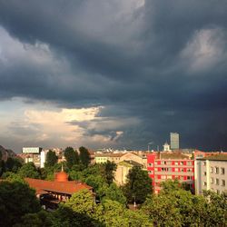 Houses in city against storm clouds