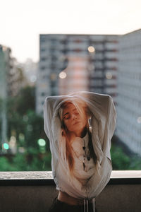 Portrait of young woman standing against built structure