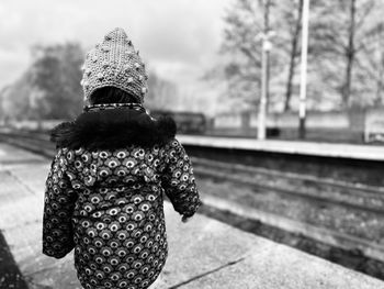 Rear view of woman standing on railroad track