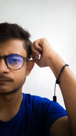 Close-up portrait of young man wearing sunglasses against wall