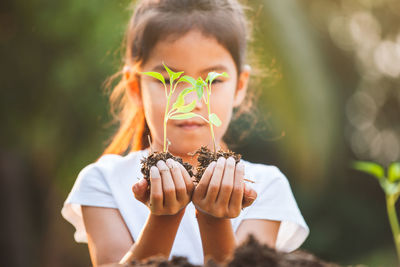 Close-up of girl holding plant in hand outdoors