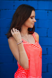 Beautiful woman standing against blue wall
