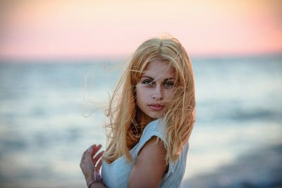 Portrait of beautiful young woman standing against sea