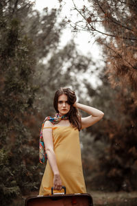 Portrait of a smiling young woman standing against trees