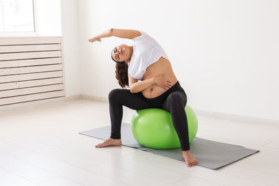 Full length of pregnant woman exercising at home