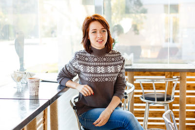 Portrait of charming young woman with friendly smile, brunette in a knitted