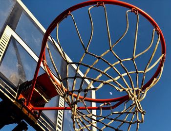 Low angle view of basketball hoop against clear blue sky with moon