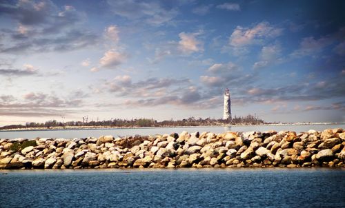 Lighthouse by sea against sky