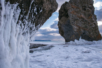 Scenic view of snow covered land and sea against sky