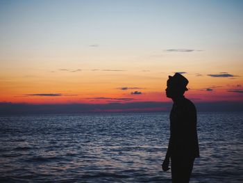 Silhouette man standing at beach during sunset