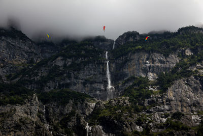 Low angle view of waterfall against sky during foggy weather