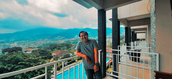 Man standing by railing against balcony