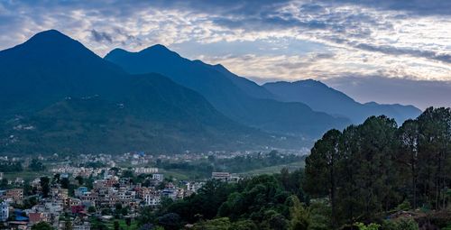 Aerial view of townscape by mountains against sky