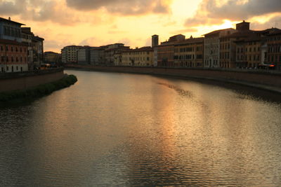 River by buildings against sky during sunset