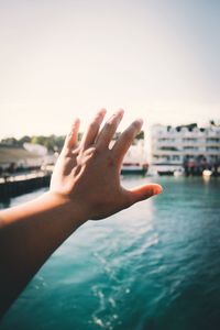 Close-up of hand against sea in city