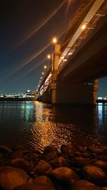 Illuminated bridge over river against sky at night