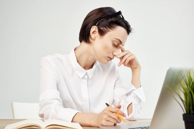 Young woman using mobile phone while sitting on table