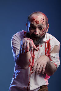 Portrait of senior man with arms crossed against black background