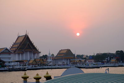 Houses and buildings against sky during sunset