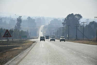 Cars on road against sky in city